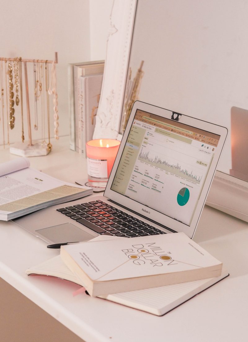 laptop on desk showing google analytics and blog books